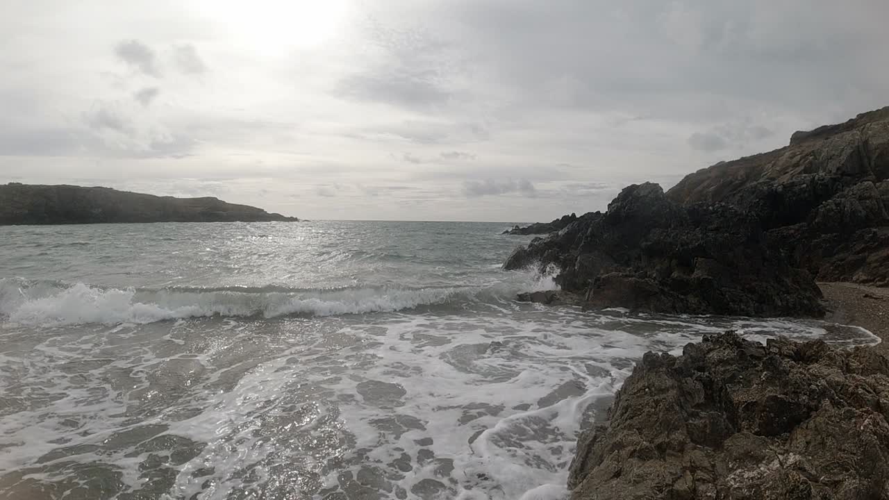 cámara lenta espumosas y brillantes olas del océano chocando contra la escarpada costa galesa al amanecer.