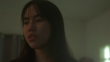 a young woman's face bears a distant expression, reflecting signs of mental illness - close up