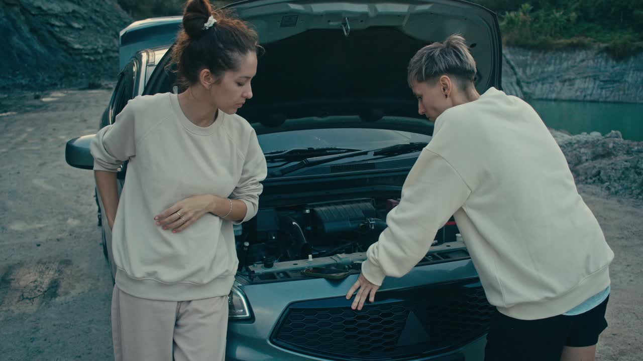 Two women troubleshooting a car breakdown in a quarry
