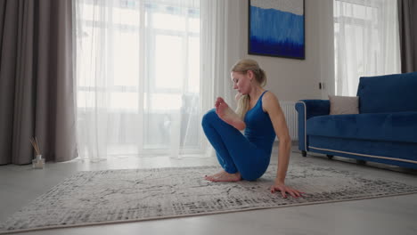 a woman at home does yoga exercises without leaving home. home training. a woman trains on the carpet in a blue suit