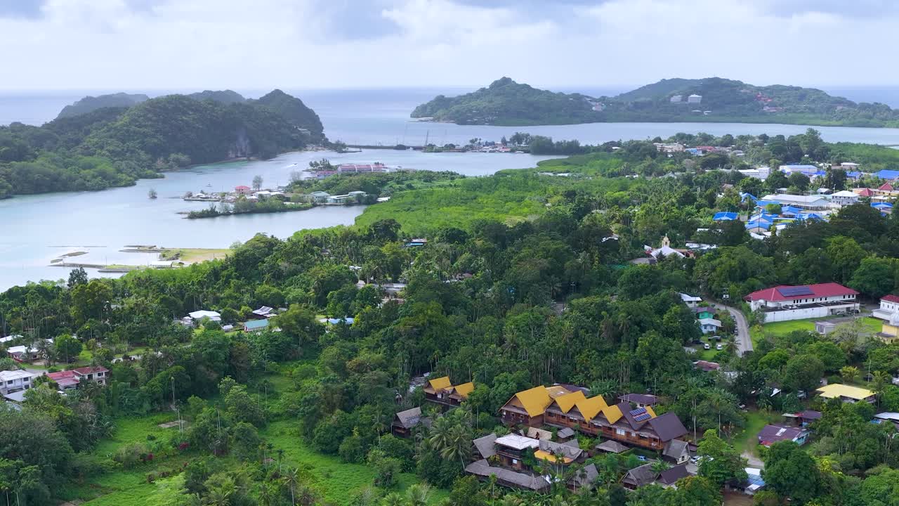 ภาพมุมสูงจากโดรนเหนือป่าเขตร้อนเขียวขจี บ้านเรือน และชายฝั่งทะเลเขตร้อน