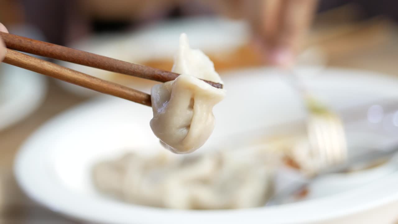 Person eating dumplings with chopsticks