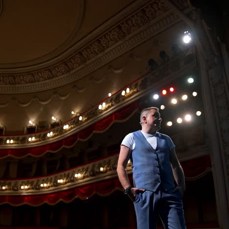 showman entertains the audience under the light, front view. big stage. serious performer speaks from the stage. hands in pockets