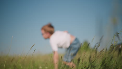 a young boy in a white shirt and short jeans is captured mid-backflip in a sunny, grassy field. the dynamic movement against the clear blue sky showcases the energy and joy of childhood play in nature