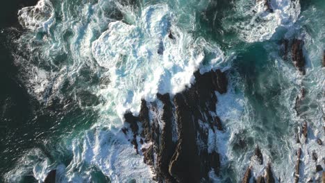 Ocean-wave-crashing-rocky-reefs-on-sea-coast,-top-down-aerial-drone-view