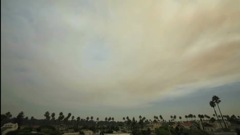 Time-lapse-of-clouds-moving-over-a-palm-trees-and-houses