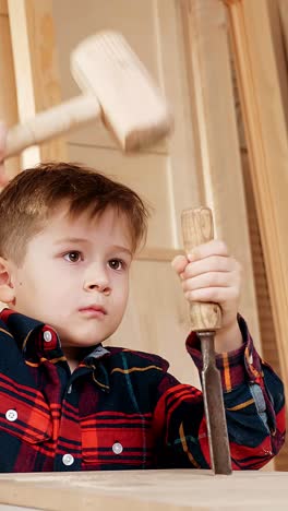 young boy focused on woodworking project, using hammer and chisel, showcasing craftsmanship and dedication in a creative workshop environment