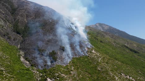 smoke and fire coming from the mountain from burning forest and scorched landscape