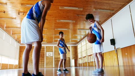 schoolboys playing basketball in basketball court