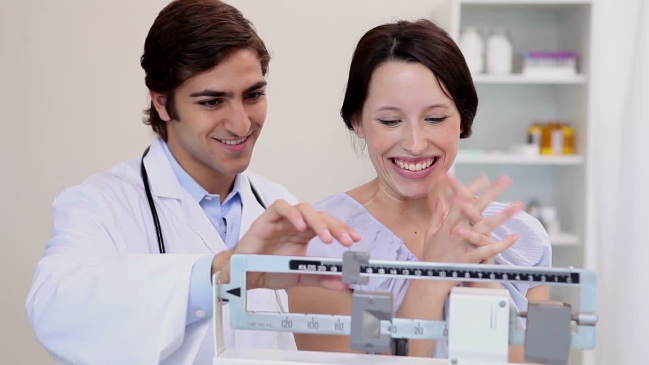 el médico pesa a una mujer.