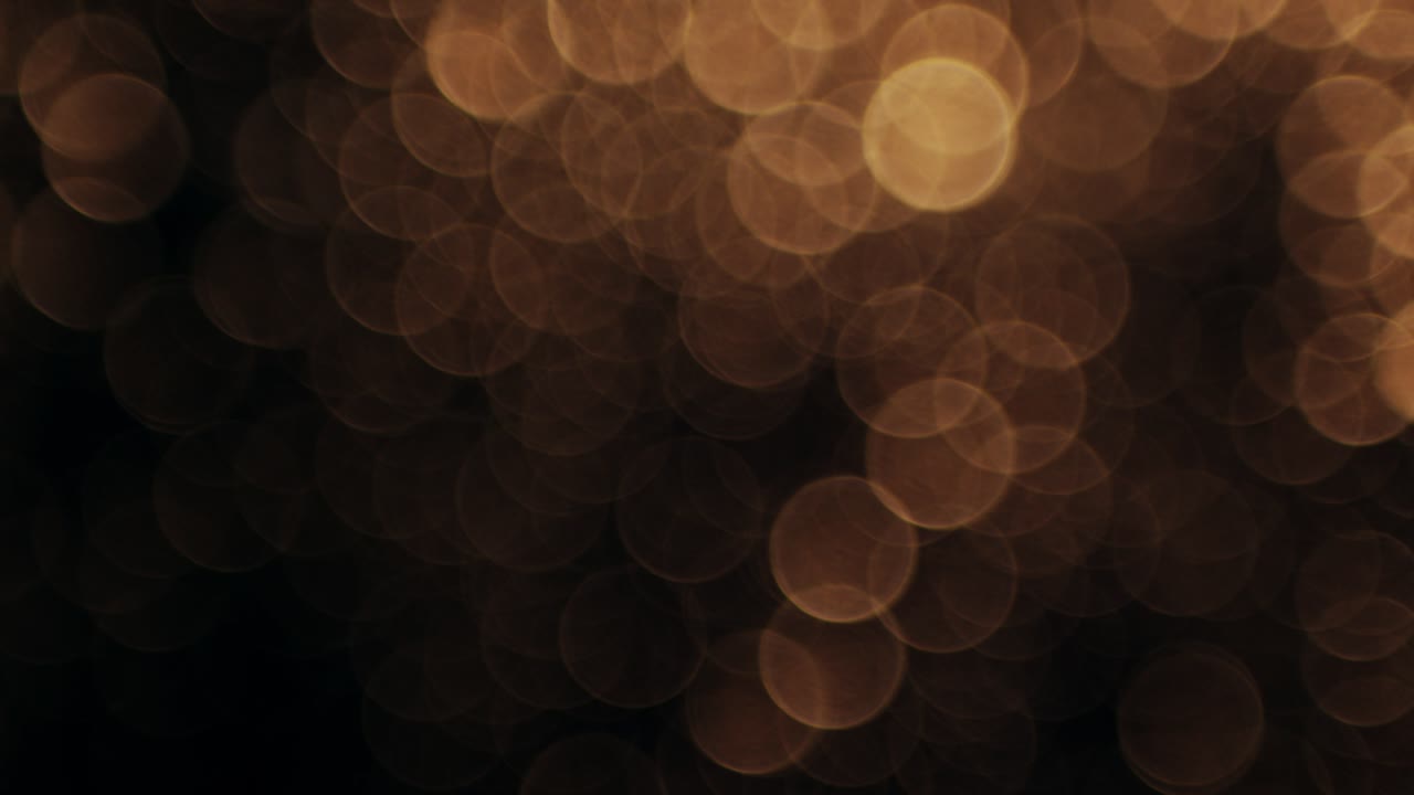 Luci bokeh dorate che appaiono e svaniscono su sfondo nero