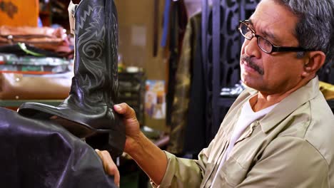 retrato de un zapatero sonriente sosteniendo una bota de cuero