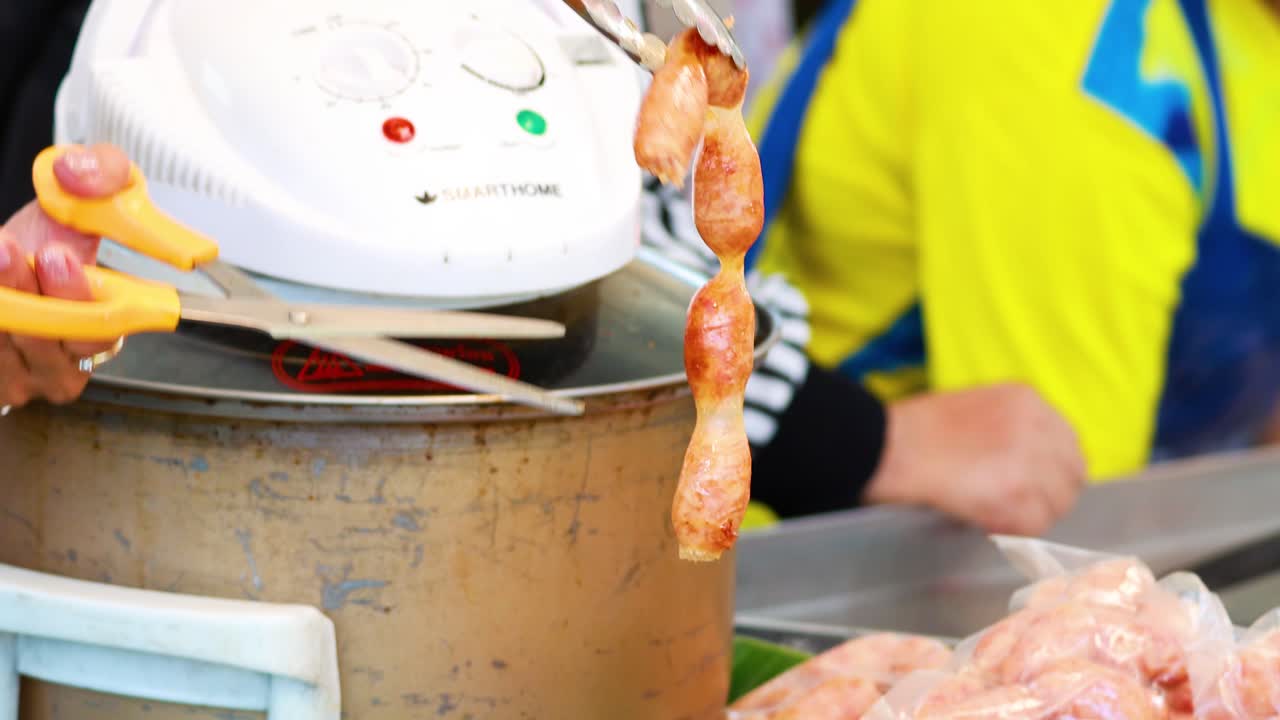 Sausages being prepared with scissors and tongs