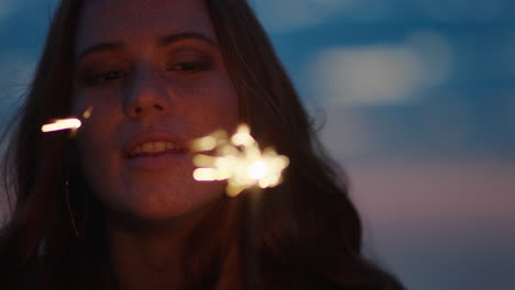 primer plano retrato de bengalas de una hermosa mujer caucásica celebrando la víspera de año nuevo disfrutando de la celebración del día de la independencia en la playa al atardecer