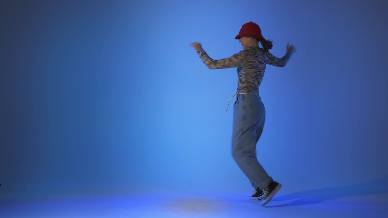 Young woman dancing house, energy jumps on blue background, studio shot