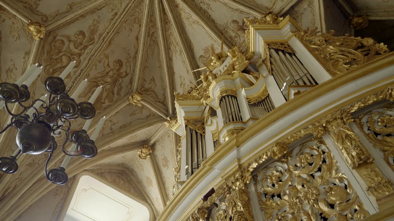 Close-up of historic organ in a castle chapel, with a classic chandelier in the foreground