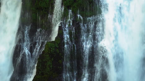 water flowing down a lush and mossy cliff at burney falls, waterfall in california