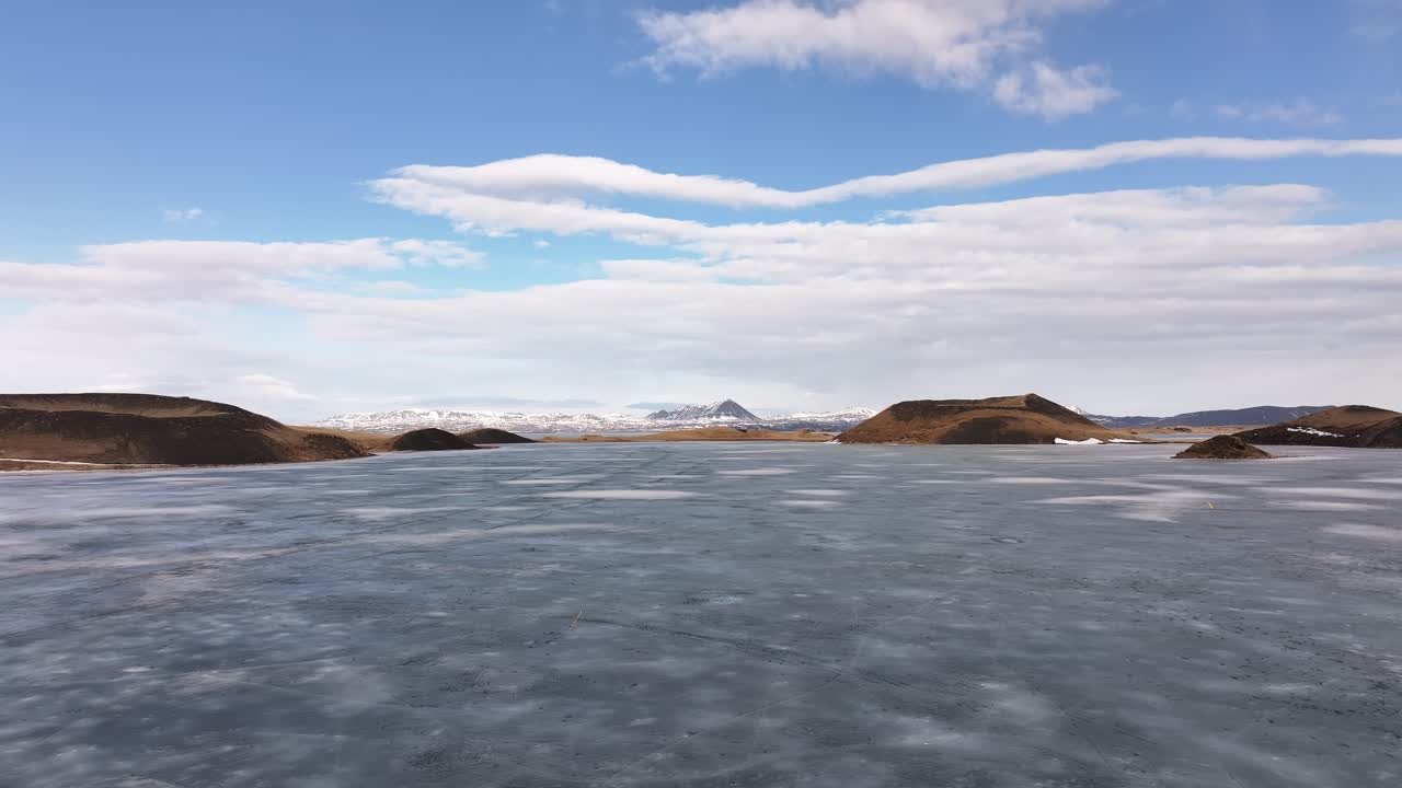 Frozen Mývatn lake with volcanic hills in Skútustaðir, Iceland, drone view of clear blue sky and snow-covered landscape in winter.