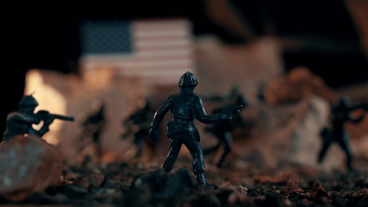 Miniature plastic toy soldiers depicting a dramatic war scene on a desolate battlefield. An american flag stands in the background