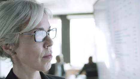 retrato recortado de una mujer de negocios con gafas mirando la pantalla