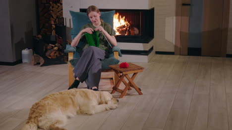 woman knitting by the fireplace with dog