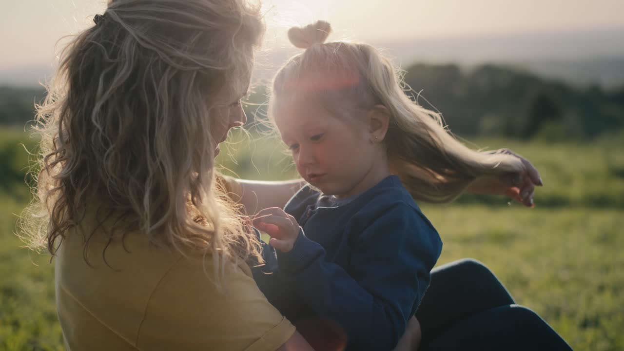 mamá con su hija pequeña sentada en el prado y unidas.