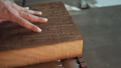 carpenter pushes a large plank of wood along a planer