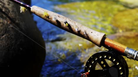 caña de pesca con mosca, carrete y gancho en roca