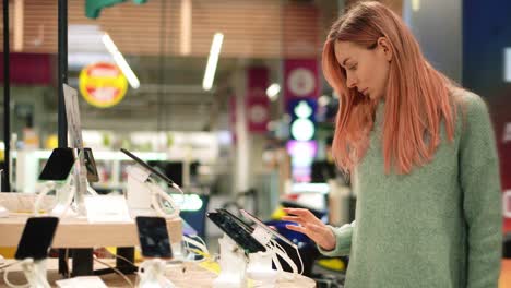 Mujer-Elige-Un-Nuevo-Teléfono-Inteligente-En-Una-Tienda-De-Electrónica