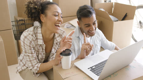 Happy-mixed-race-couple-discuss-while-using-laptop