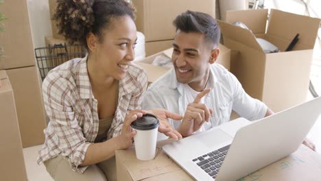 feliz pareja de raza mixta discute mientras usa la computadora portátil