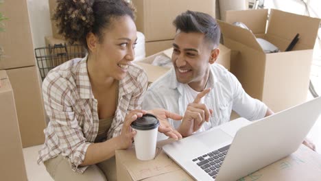 happy mixed race couple discuss while using laptop