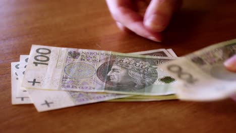 man counts money, cash polish zloty, close-up 100 pln, money on the table