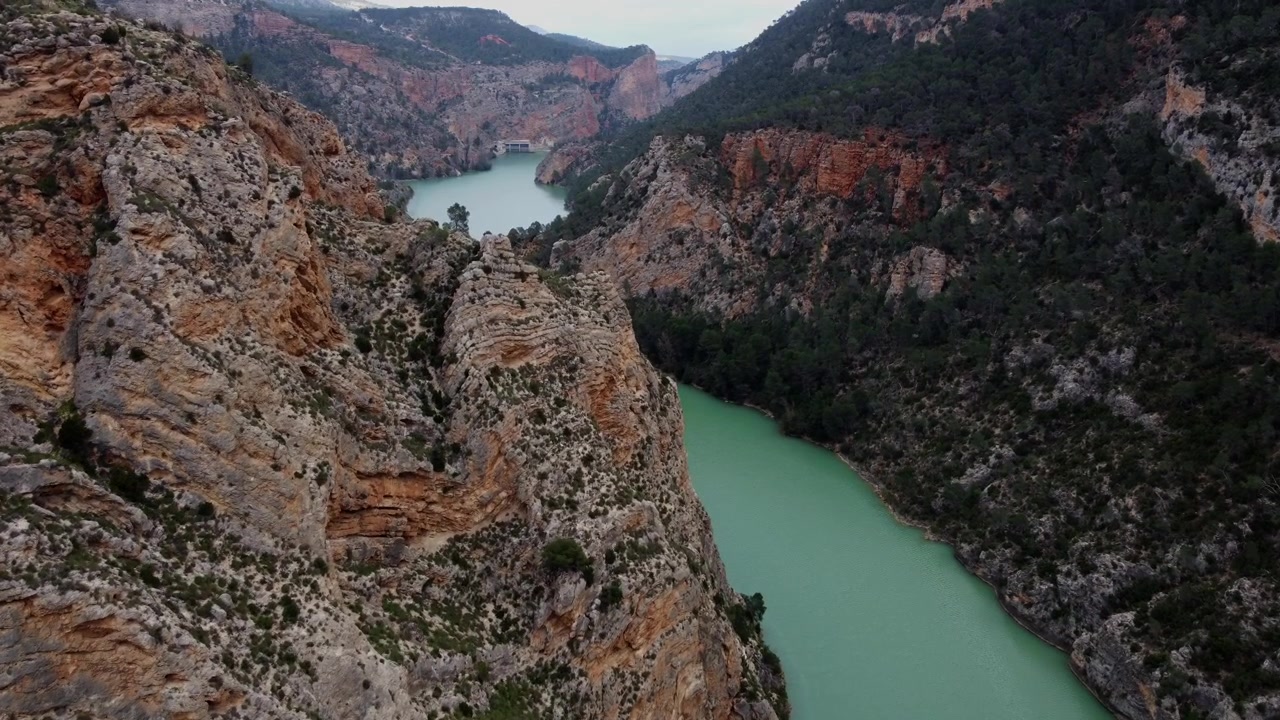 Spektakulær 4K droneflyvning over den turkise Júcar-elven i Spania, navigerer gjennom en dyp kløft med massive klipper og frodige skogkledde skråninger.