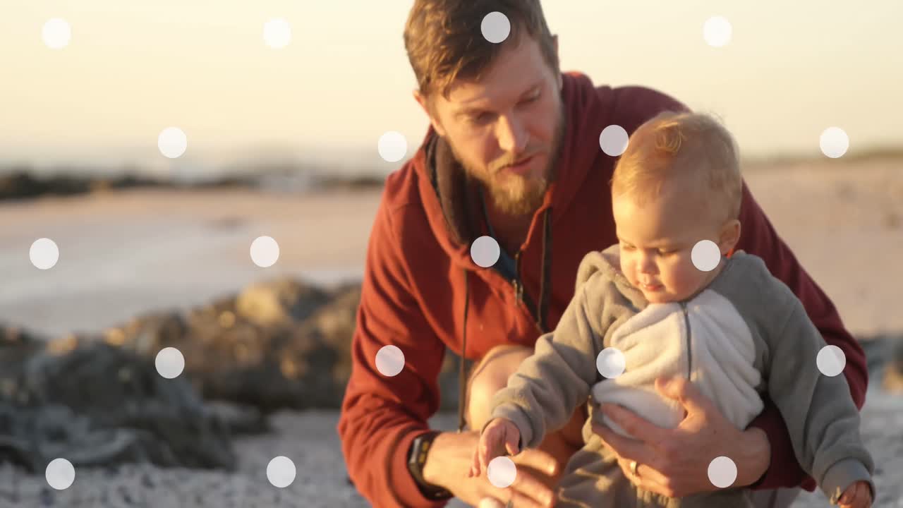 Animation of white spots falling over caucasian father with baby