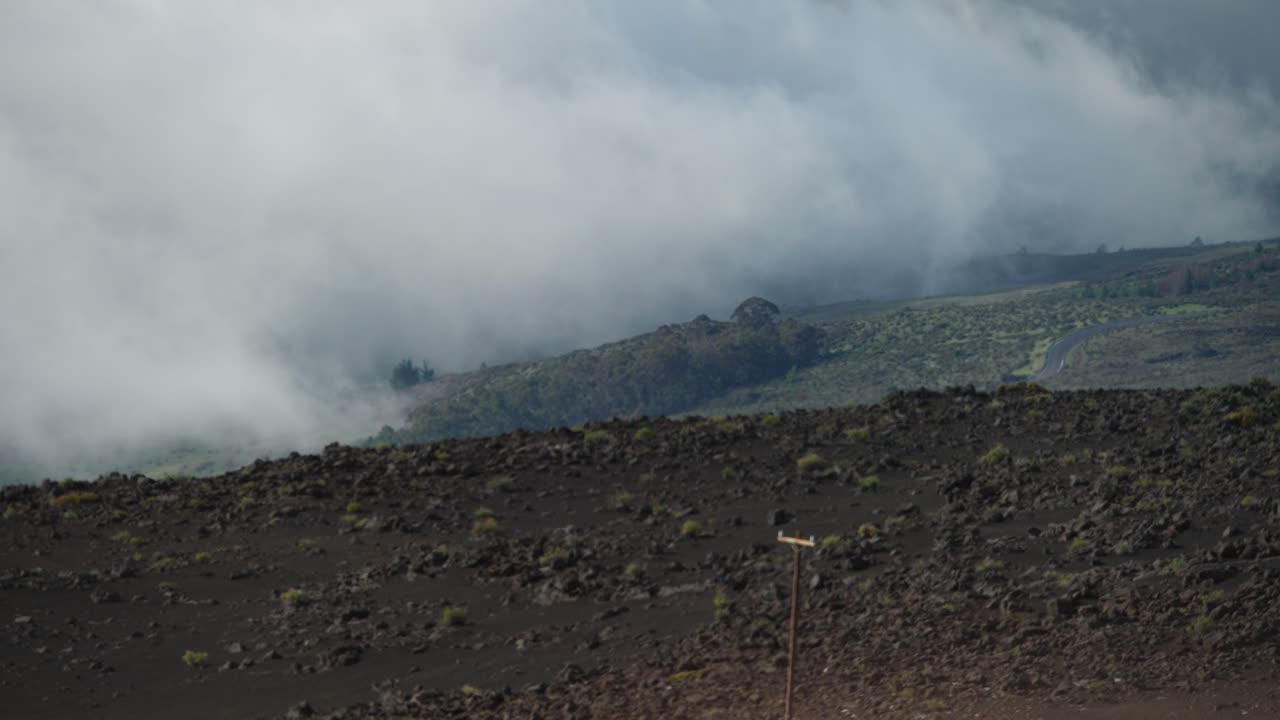 nubes de niebla rodan sobre el terreno rocoso de la montaña haleakala en maui