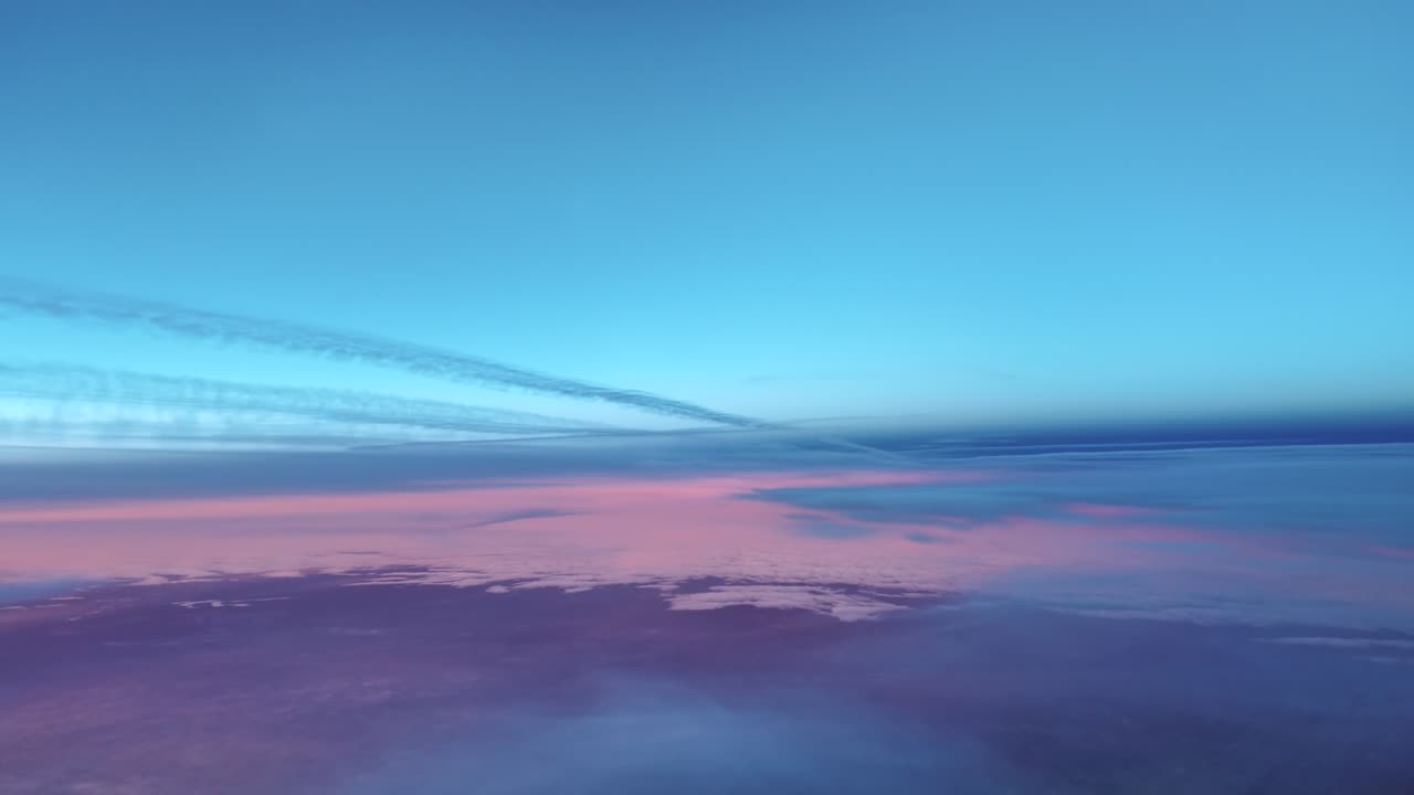 Estelas de condensación al amanecer con un horizonte púrpura, capturadas desde la cabina de un avión a reacción volando por debajo entre capas de nubes etéreas