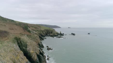 Aerial-tracking-along-a-rough-rugged-rocky-and-jagged-Devon-coastline-in-the-UK