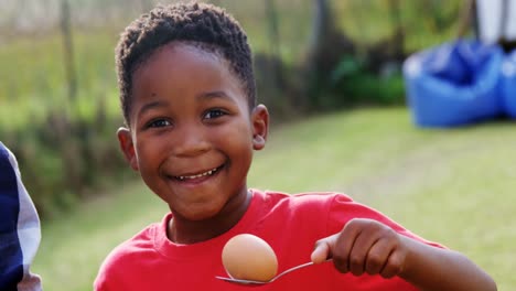 happy boy holding egg and spoon in backyard 4k