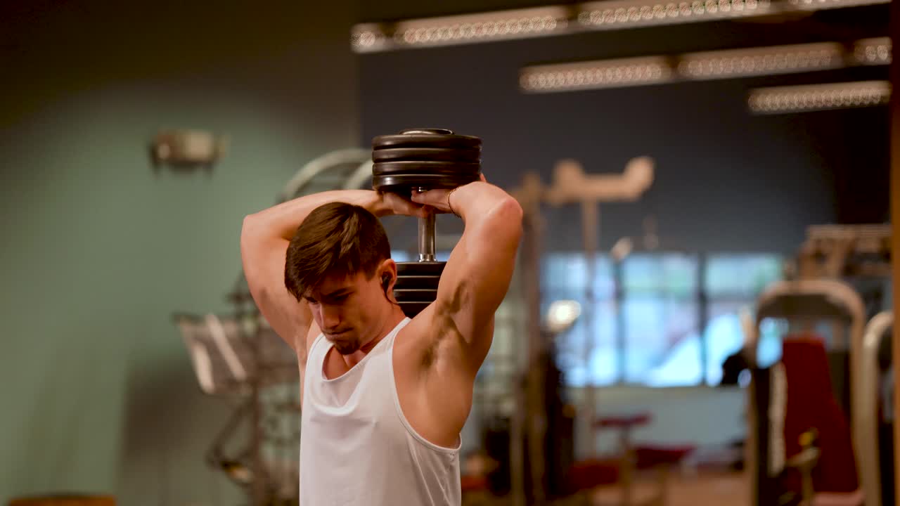 오버헤드 삼두근 프레스나 확장을 하고 있는 잘생긴 10대 보디빌더의 근접 촬영