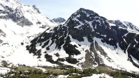 Sobrevuelo-Aéreo-Panorámico-Sobre-El-Lago-Mässersee-Con-Vistas-Al-Valle-Remoto-Cubierto-De-Nieve-De-Binntal-En-Valais,-Suiza-A-Principios-De-Verano