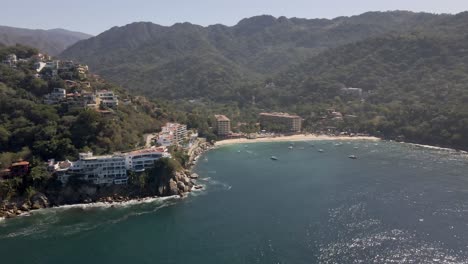 Mismaloya-Beach-The-colorful-Sierra-Madre-Mountains-meet-the-serene-waters-of-the-Mexican-Pacific-Ocean-at-the-beach-of-Mismaloya,-a-quaint-fishing-village-just-15-minutes-south-of-Puerto-Vallarta