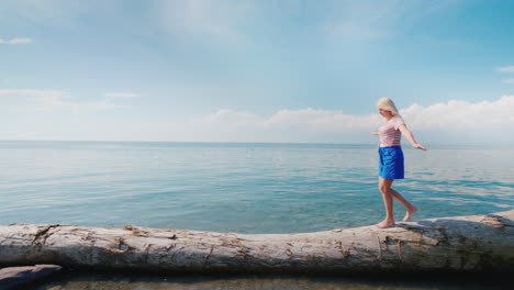 a focused woman walks along a log maintains balance with her hands