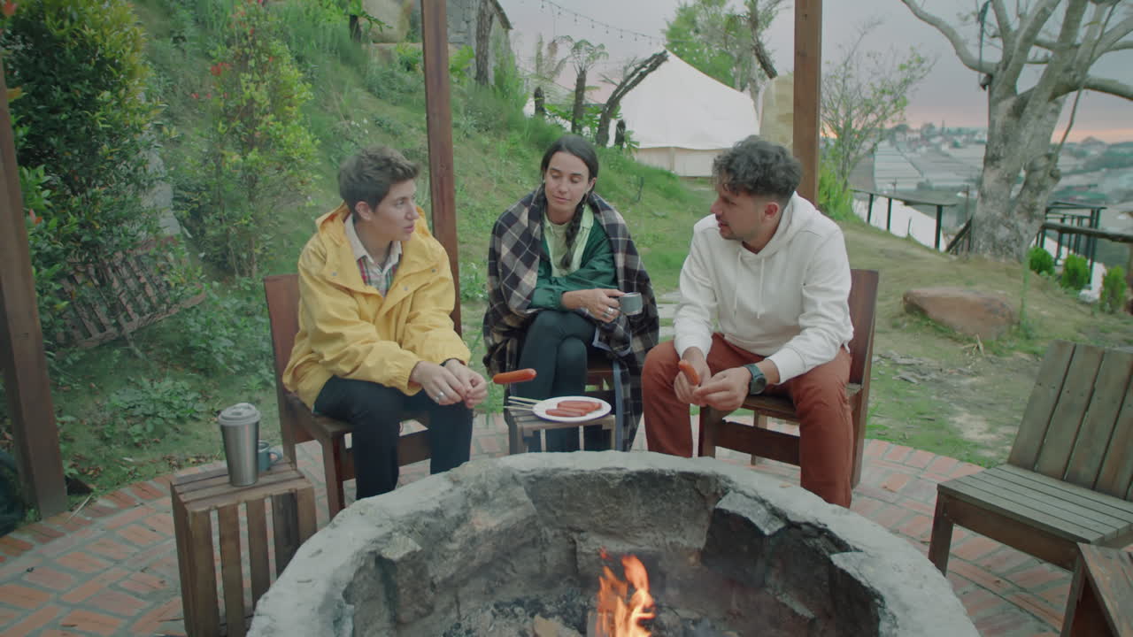 Tourists Having Meal and Talking by Campfire at Glampsite