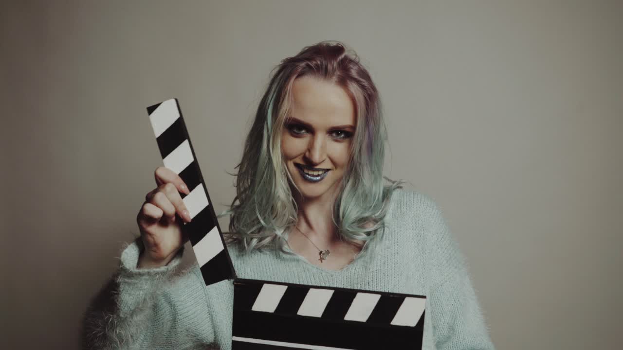 Woman playing with a clapboard. Portrait of a happy woman playing with a clapboard in studio