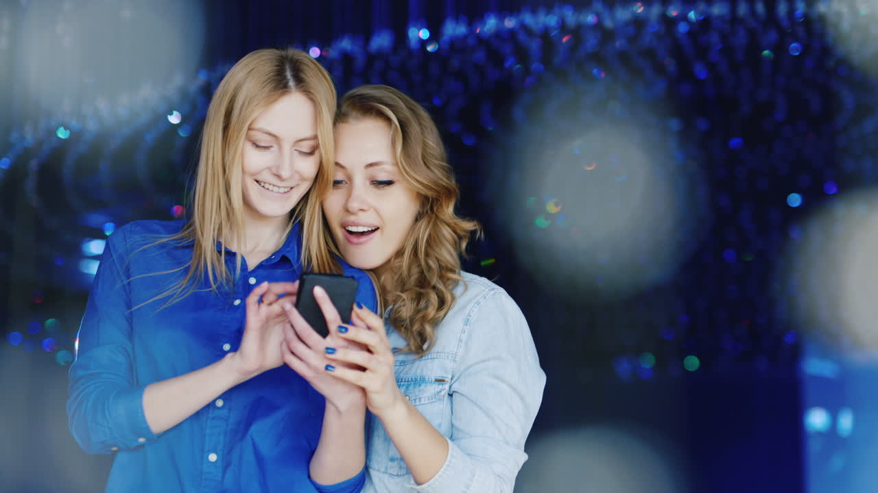 dos mujeres jóvenes usan un teléfono inteligente y se divierten 3