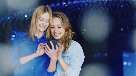 two young women use a smartphone and have a good time 3