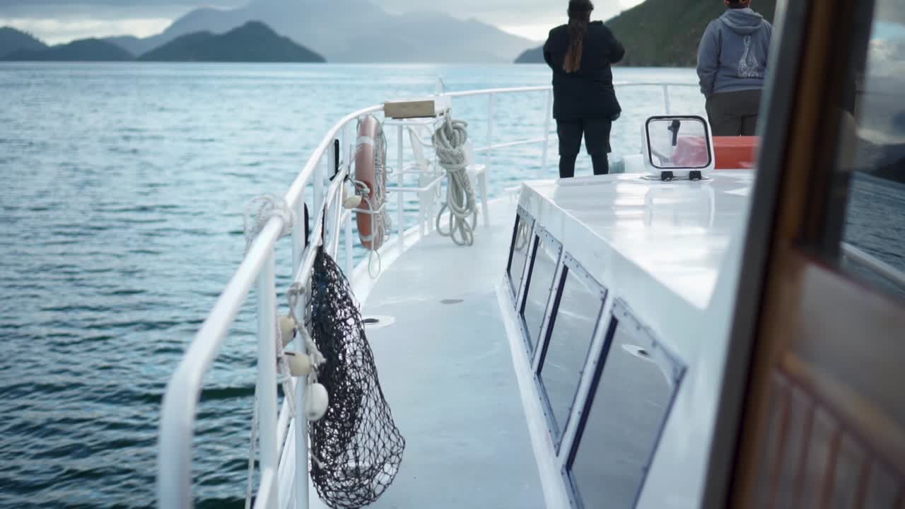 ZEITLUPE - Personen stehen auf dem Bugdeck eines Kreuzfahrtschiffs, sprechen und betrachten die Landschaft in den Marlborough Sounds, Neuseeland