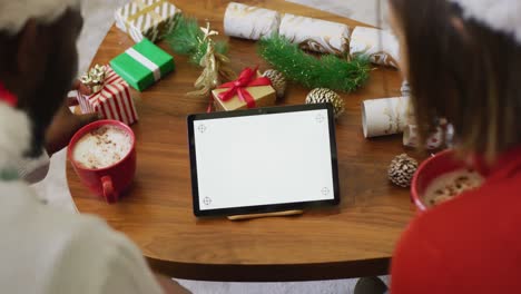 Video-of-happy-diverse-couple-making-christmas-video-call-on-tablet-at-home,-copy-space-on-screen