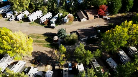 toma aérea de un parque de vehículos recreativos en otoño con muchos campistas a lo largo de la carretera, estacionados en un campamento